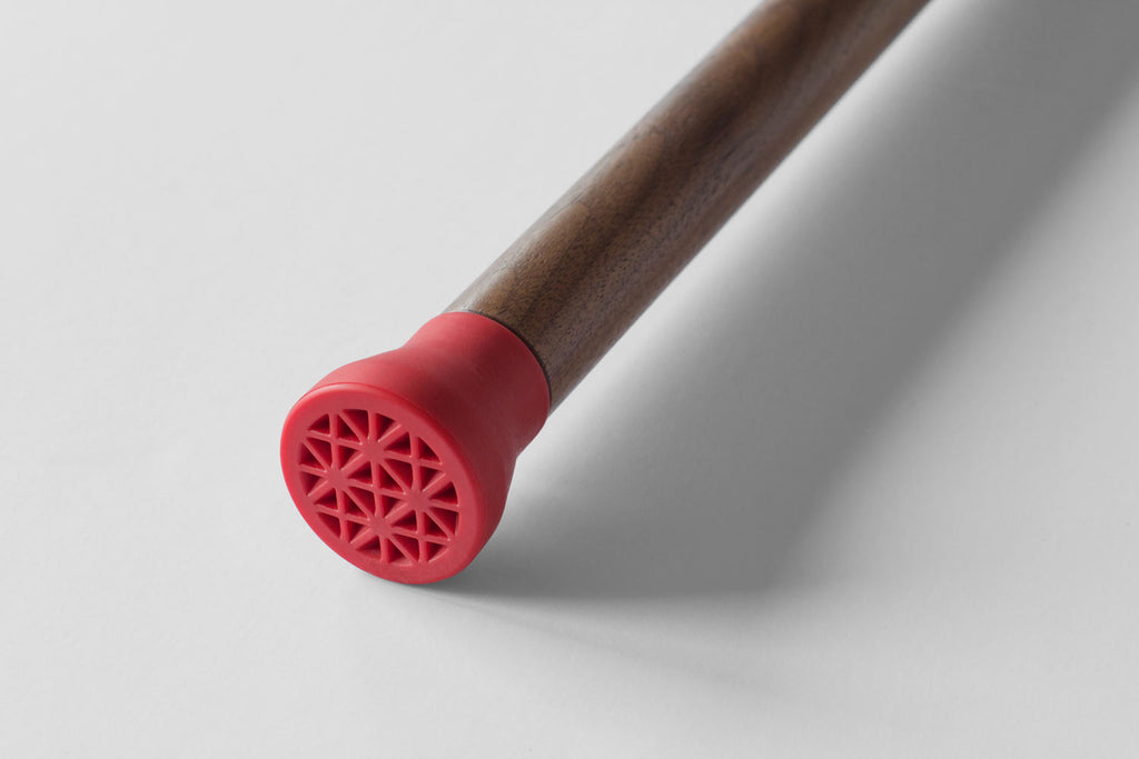 closeup of contemporary walnut walking stick with red rubber tip